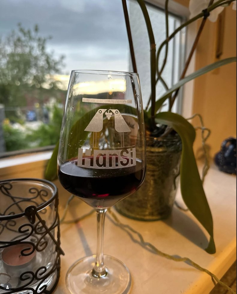 Ein Glas Rotwein mit hansi-Logo